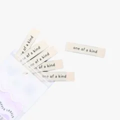 Weitere Ansicht der Labels 'one of a kind' beim Herausfallen aus der Verpackung.