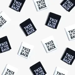 Mehrere weiße und schwarze Labels 'This is The Back' verstreut als Flatlay angeordnet
