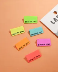 Die Neonfarben-Labels 'Quality Shit' locker auf pfirsichfarbenem Untergrund neben der Verpackung
