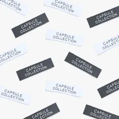 Mehrere Labels 'Capsule Collection' in Schwarz und Weiß verstreut in der Draufsicht.