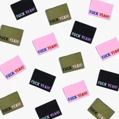 Mehrere Labels 'Fuck Yeah!' in allen drei Farben verstreut in der Draufsicht.
