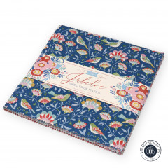 Tilda Layer Cake „Jubilee“, Stapel mit blauem Vogel-Blumen-Design und Kollektionsbanderole, schräg liegend fotografiert.