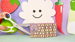 Mehrere KATM Adventskalender nebeneinander vor Papierdeko mit Erdbeere, Chili und Schere