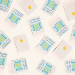 Weitere Nahaufnahme der Koffer-Weblabels mit goldenen Herz- und Rechteck-Akzenten und einfarbiger Herz-Rückseite.