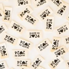 Weitere Nahaufnahme der „Made in 2024"-Weblabels in schwarzem Siebdruck auf cremefarbenem Stoff.
