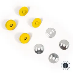 Vier gelbe Magnetverschluss-Oberteile und vier silberne Unterlegscheiben in versetzter Anordnung, freigestellt auf weißem Hintergrund.