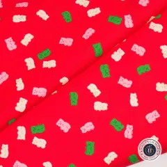 Diagonal gefalteter roter Baumwollstoff mit gestreuten Gummibärchen in Rosa, Creme und Grün