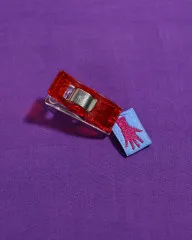 Pinkes Mini-Hand-Label mit Nähclip auf violettem Stoff