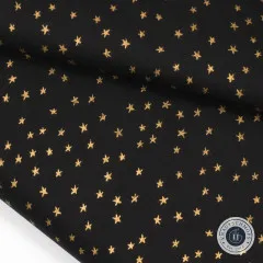 Nahaufnahme des gefalteten Stoffes Mini Starry mit goldglänzenden Sternen auf schwarzem Baumwollgrund