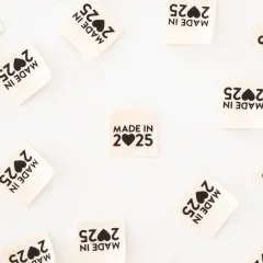 Alle acht „Made in 2025"-Endfalt-Weblabel verstreut, teils quer liegend.