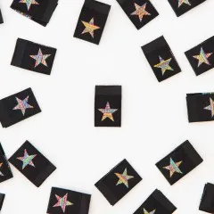 Alle acht „Metallic Rainbow Star"-Weblabel verstreut, teils quer liegend.