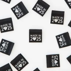 Alle acht „Made in 2025"-Weblabel verstreut, teils auf dem Kopf liegend.
