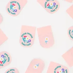 Rosa Weblabels mit Blumenstrauß-Aufdruck und Schriftzug „Good Things Take Time" sowie Rückseite mit einzelner Gänseblümchen-Blüte.