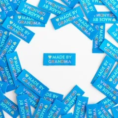 Mehrere türkisblaue Weblabels "Made by Grandma" im Kreis um ein einzelnes zentrales Label angeordnet.