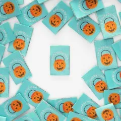 Mehrere mintgrüne Weblabels mit Kürbiseimer-Motiv im Kreis um ein einzelnes zentrales Label angeordnet.