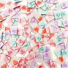 Dichte Nahaufnahme vieler verstreuter Bonbonherz-Weblabels mit unterschiedlichen Liebesbotschaften.