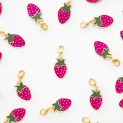 Mehrere Strawberry-Zipper-Charms locker verstreut auf weißem Untergrund.