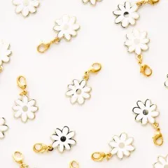 Mehrere White-Daisy-Zipper-Charms locker verstreut auf weißem Untergrund.