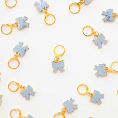 Mehrere Blue-Bow-Zipper-Charms locker verstreut auf weißem Untergrund.