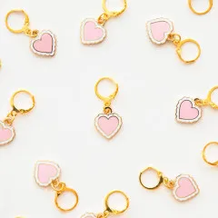 Mehrere Sweet-Heart-Zipper-Charms locker verstreut auf weißem Untergrund.