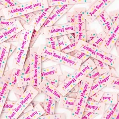 Dichte Nahaufnahme vieler verstreuter „Just Sew Happy"-Weblabels mit bunten Konfettipunkten.