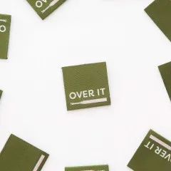 Mehrere „Over It“-Labels locker verstreut auf weißem Untergrund.