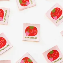 Mehrere Tomato-Pin-Cushion-Weblabels locker verstreut auf weißem Untergrund.