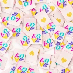 Dichte Nahaufnahme vieler verstreuter Weblabels, abwechselnd mit geometrischem „LOVE"-Schriftzug auf der Vorder- und goldenem Herz auf der Rückseite.