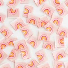 Dichte Nahaufnahme vieler verstreuter rosafarbener Weblabels mit Regenbogenmotiv.