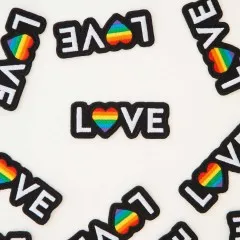 Nahaufnahme mehrerer „Love"-Patches mit Regenbogen-Herz als O, dicht verstreut.