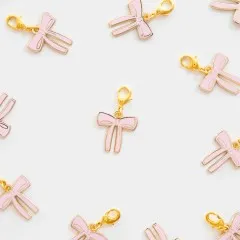 Mehrere Pink-Bow-Zipper-Charms locker verstreut auf weißem Untergrund.