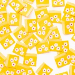Dichte Nahaufnahme vieler verstreuter gelber Weblabels mit weißen Gänseblümchen.