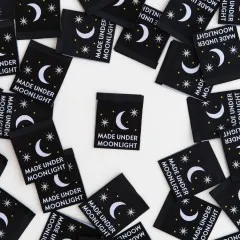 Mehrere schwarze Sarah-Hearts-Weblabels „Made Under Moonlight" mit Mond- und Sternmotiv, ein Label mittig freigestellt.