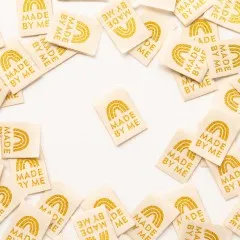 Mehrere cremefarbene Weblabels mit goldenem Regenbogen-Motiv im Kreis um ein einzelnes zentrales Label angeordnet.
