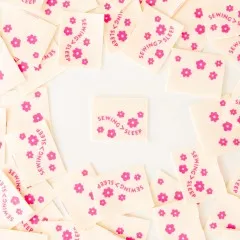 Sarah Hearts Weblabels mit Blütenmotiv, teils mit Schriftzug „Sewing > Sleep", kreisförmig um ein einzelnes Label angeordnet.