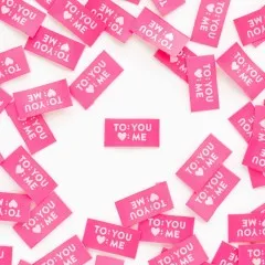 Mehrere pinke Weblabels "To: You, Herz: Me" im Kreis um ein einzelnes zentrales Label angeordnet.