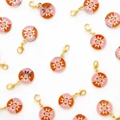 Weitere Ansicht mehrerer verstreuter Zipper Charms in Rosa- und Orangetönen.