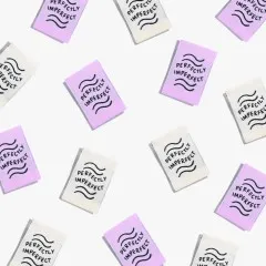 Zahlreiche „Perfectly Imperfect"-Labels in Elfenbein und Flieder als Flatlay-Musteraufnahme locker verstreut.