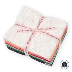 Makroaufnahme des cremefarbenen Konfetti-Punkte-Musters mit rosa Markenband Poppie Cotton