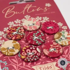 Nahaufnahme der stoffbezogenen Knöpfe mit floralen und gepunkteten Mustern in Rot.