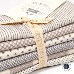 Aufgefächerter Stapel der sechs Classic-Basics-Muster: Streifen, Punkte, Sterne und Karo in Grau.