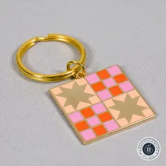 Nahaufnahme des Schlüsselanhängers mit Quilt-Sternmuster auf grauem Stoff.