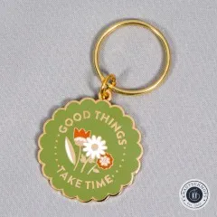 Nahaufnahme des Schlüsselanhängers mit Blumenmotiv auf grauem Stoffuntergrund.