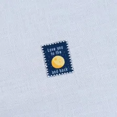 Nahaufnahme des „Love You To The Moon and Back"-Labels mit Zickzack-Kante auf weißem Stoff.