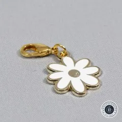 Nahaufnahme des weißen Gänseblümchen-Anhängers mit Karabiner auf grauem Stoffuntergrund.