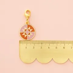 Detailaufnahme des Anhängers mit Karabinerhaken auf grauem Stoff.