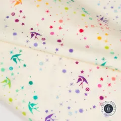 Nahaufnahme des diagonal gefalteten Stoffs „Fairy Dust“ in Cotton Candy, bunte Schwalben- und Sternchen-Motive gut erkennbar.