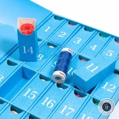 Nahaufnahme der nummerierten Fächer mit geöffnetem Türchen 14 und herausgenommener blauer Aurifil-Garnspule.