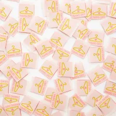 Viele Sarah Hearts Weblabels „Hang Dry" mit Kleiderbügel-Motiv dicht verstreut, Nahaufnahme.