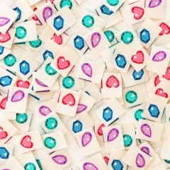 Viele bunte Sarah Hearts Edelstein-Weblabels in verschiedenen Formen und Farben dicht verstreut, Nahaufnahme.
